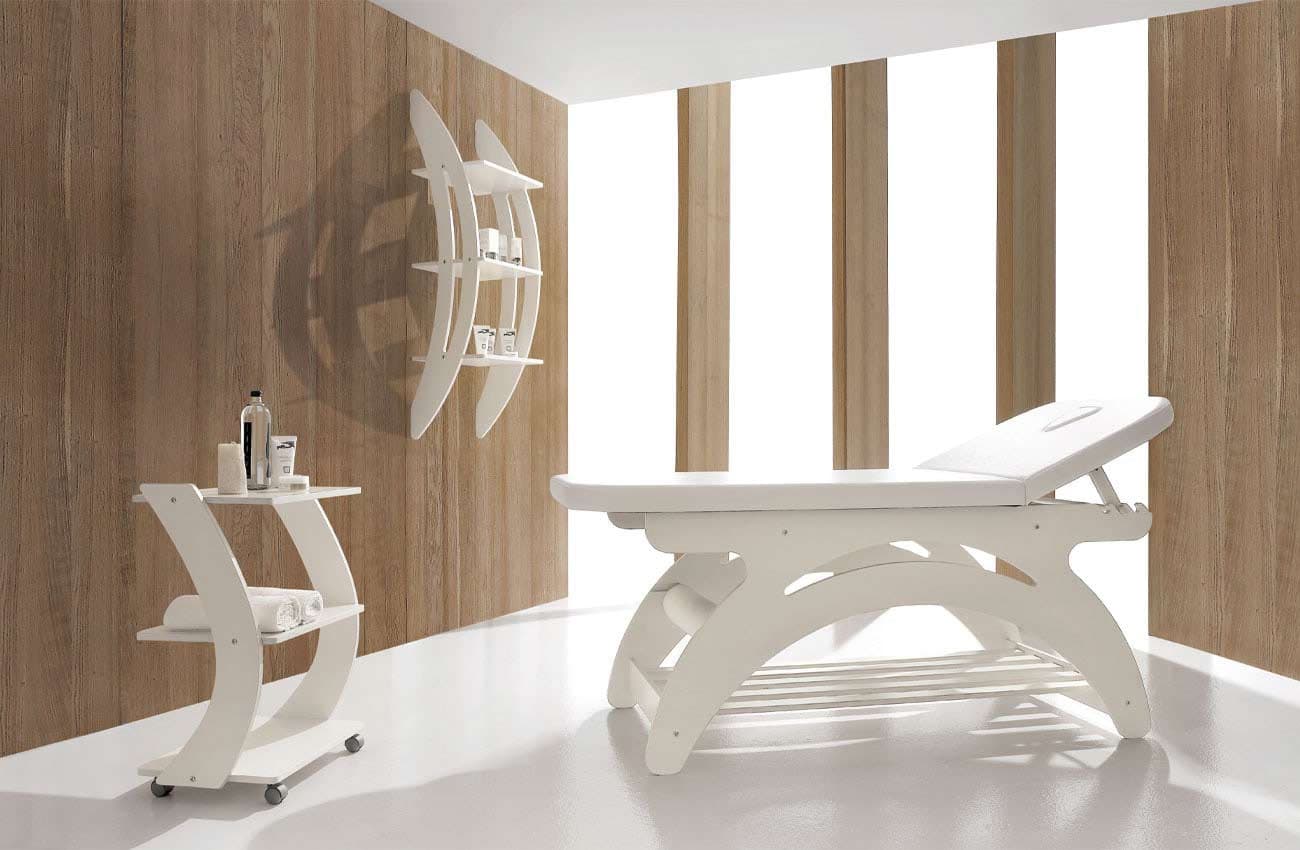 Cabina estetica Vismara con lettino bianco dalle linee curve, carrello e pareti rivestite in legno chiaro