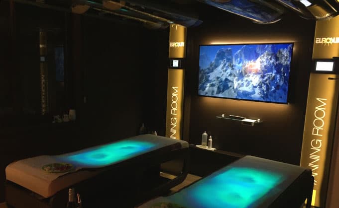 Sala E-Sense con due lettini illuminati da luce cromoterapica e schermo a parete