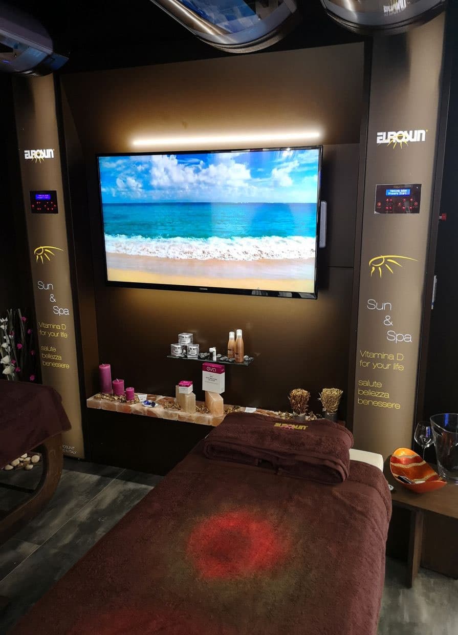 Cabina E-Sense con lettino, schermo con paesaggio marino e prodotti su una mensola