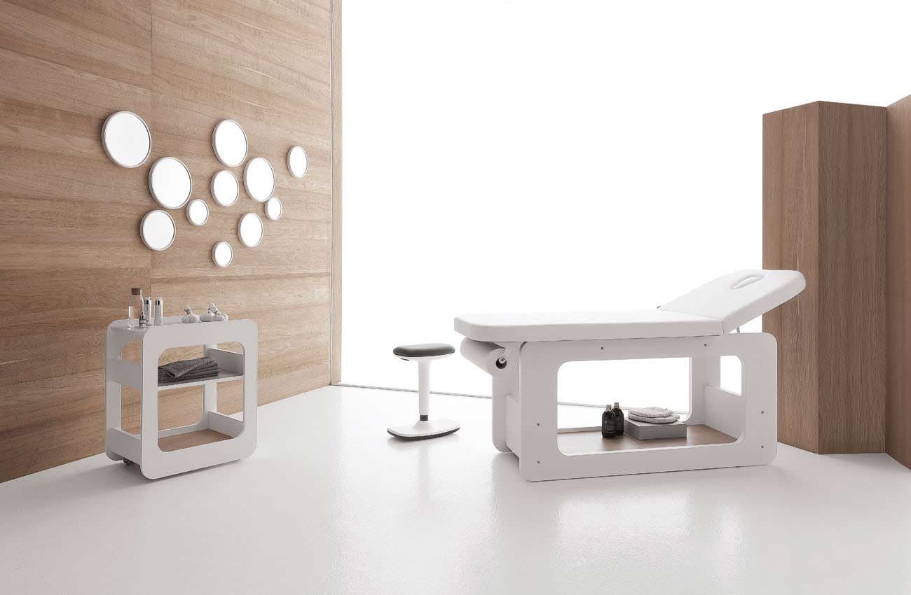 Cabina estetica Vismara con lettino bianco, sgabello, carrello portaoggetti e specchi rotondi a parete